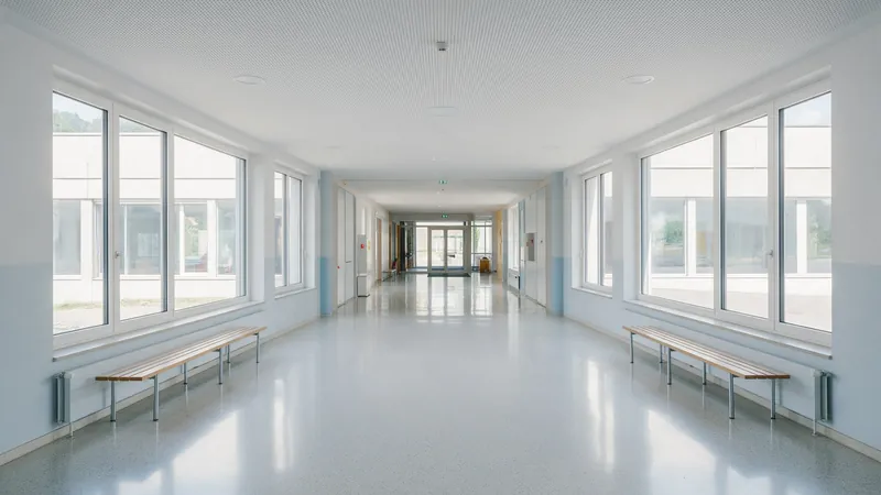 Breiter, frisch gereinigter Gang eines Schulhauses mit Sitzbänken und grossen Fenstern